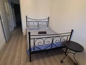 a bed with a black frame and a table in a room at APPARTEMENT EN PLEIN CENTRE VILLE PESSAC AVEC 3 CHAMBRES in Pessac