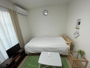um pequeno quarto com uma cama, uma mesa e uma televisão em One Point Five em Tóquio