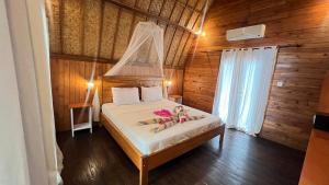 Un dormitorio con una cama con zapatillas y flores. en Gita Gili Bungalow en Gili Air