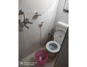 een badkamer met een toilet en een roze emmer bij Hotel Kumar Kripa, Gaya in Gaya