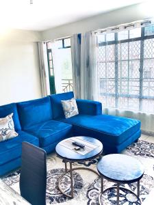 STUDIO MAIYAN في Busia: غرفة معيشة مع أريكة زرقاء وطاولتين