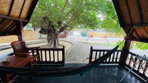 un porche con una hamaca y un árbol en Gita Gili Bungalow en Gili Air
