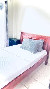 Una cama con sábanas blancas y almohadas. en STUDIO MAIYAN, en Busia