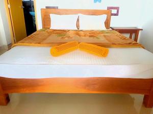 a wooden bed with two yellow ties on it at 1to1 Cottage Ella in Ella