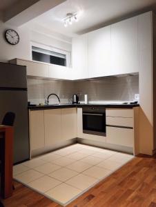 a kitchen with white cabinets and a clock on the wall at Velesajam in Zagreb