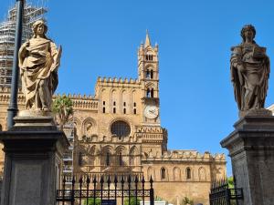 un edificio con una torre de reloj y una estatua en La Loggia dei Re, en Palermo