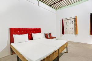 een slaapkamer met een groot bed met een rood hoofdeinde bij Super OYO Unnati Farm And Resort in Nūrpur