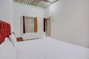 een witte kamer met een bed en een stoel bij Super OYO Unnati Farm And Resort in Nūrpur