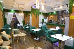a restaurant with green chairs and tables at فندق نبض المخلاف in Şāmitah