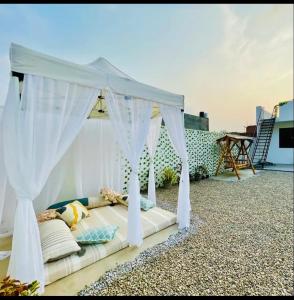 a white canopy bed on a patio with a table at Centaurus Pvt. villa with lawn in Noida