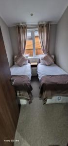 a small room with two beds and a window at Castlewood lodge in Banchory