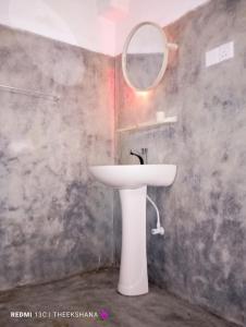La salle de bains est pourvue d'un lavabo blanc et d'un miroir. dans l'établissement Villa Hasi, à Habaraduwa Central