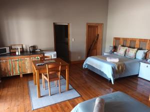 a bedroom with a bed and a desk and a table at Featherhouse in Colesberg