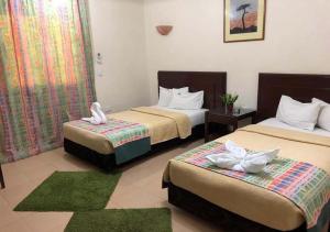 um quarto de hotel com duas camas com tapetes verdes em Bonne Vie Studios em Cidade 6 de Outubro