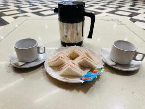 een tafel met twee kopjes en een bord met broodjes bij Chowdhry Tourist Lodge - New Delhi Railway Station - 2 minutes walk in New Delhi