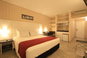 a bedroom with a large bed and a kitchen at Hotel Confiance Prime Batel in Curitiba