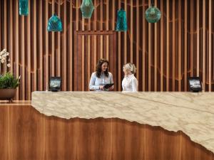 two women standing at a reception desk with their phones at The Chedi Luštica Bay in Tivat +37 photos