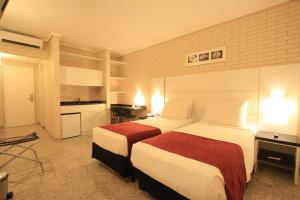 een hotelkamer met 2 bedden en een keuken bij Hotel Confiance Prime Batel in Curitiba