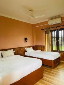 1 dormitorio con 2 camas y techo en sauraha alley inn en Chitwan