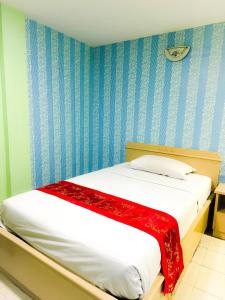 uma cama num quarto com paredes azuis e brancas em Woodlands Inn em Bangkok