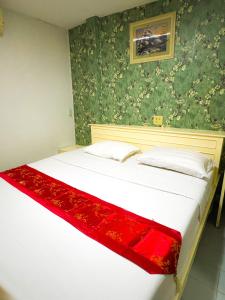 um quarto com uma cama branca e um cobertor vermelho em Woodlands Inn em Bangkok