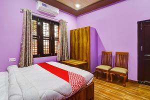 um quarto com paredes roxas, uma cama e 2 cadeiras em OYO Hari Leela Home Stay em Haldwani