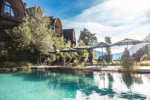 a pool of water with umbrellas and tables and chairs at Himmelchalet - Alpencamping Nenzing in Nenzing