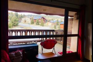 a view from a window of a balcony with a red chair at Petit cocon des montagnes in Bolquere Pyrenees 2000