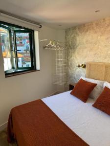ein Schlafzimmer mit einem Bett mit zwei Kissen und einem Fenster in der Unterkunft CASA URBANIN III centro de cudillero in Cudillero