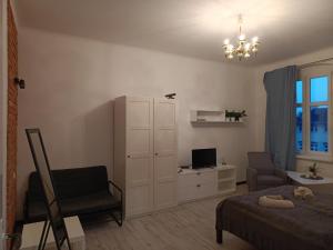 um quarto com uma cama, uma cadeira e uma televisão em Kamienica Nowodworska 30 em Bydgoszcz