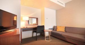 a hotel room with a couch and a desk and a television at Richmond Hotel Tokyo Shiba in Tokyo