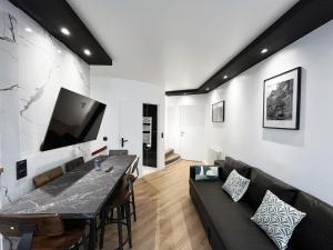 uma sala de estar com um sofá preto e uma televisão em Urban Flat 172 - Pretty Flat Gaite Montparnasse Cinema em Paris