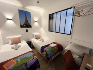 duas camas num quarto com a torre Eiffel em Urban Flat 172 - Pretty Flat Gaite Montparnasse Cinema em Paris