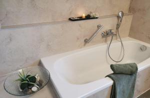a bathroom with a bath tub with a candle and a towel at Schöne, helle, ruhige Wohnung und Wellness Sauna 