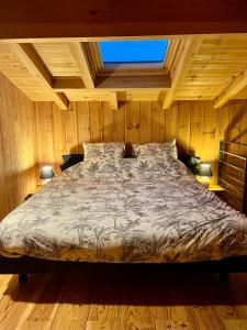 um quarto com uma cama num quarto de madeira em La cabane du Broustic em Andernos-les-Bains