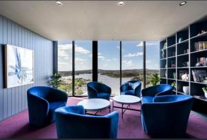 a waiting room with blue chairs and tables and windows at Lakeside Apartment with Great Views in Belconnen
