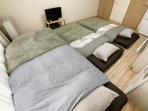 a group of three beds in a room at Shinsanjo Building - Vacation STAY 15855 in Asahikawa