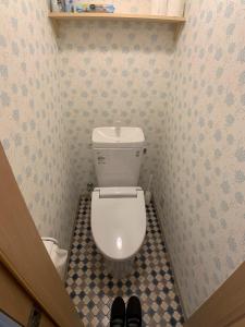 a small bathroom with a toilet and a pair of shoes at Shinsanjo Building - Vacation STAY 15855 in Asahikawa