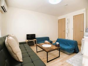 a living room with a green couch and two blue chairs at Shinsanjo Building - Vacation STAY 15855 in Asahikawa