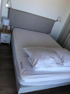 un grand lit blanc avec une tête de lit et une lampe dans l'établissement Cabourg Face A La Mer, à Cabourg