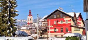 ゴレンスカ地方にあるPONI NAKLO - Sobe Marinšekの時計塔と教会のある赤い建物
