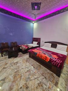 1 Schlafzimmer mit 2 Betten und violetter Beleuchtung in der Unterkunft Shri Radha Rani Bhawan in Vrindāvan