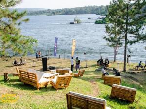 a group of people sitting on the grass near a lake at Nile Park Jinja in Jinja