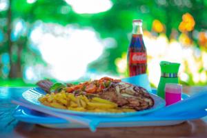 a plate of food with meat and french fries on a table at Nile Park Jinja in Jinja