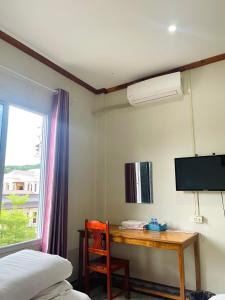 1 dormitorio con escritorio, TV y cama en Hammer Guesthouse, en Luang Namtha