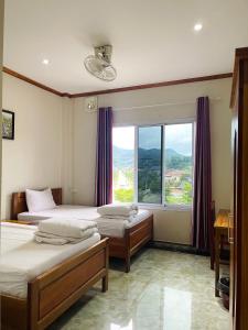 a bedroom with two beds and a large window at Hammer Guesthouse in Louang Namtha