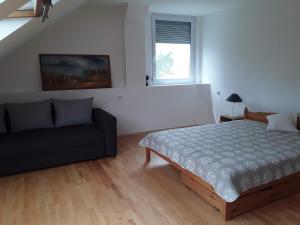 1 dormitorio con cama y sofá en Családi apartman en Tapolca