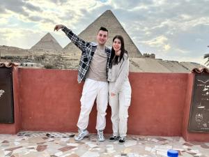 a man and a woman standing in front of the pyramids at Energy Of Pyramid Hotel in Cairo