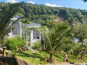 a building with palm trees in front of a mountain at Bungalow BIỂN ĐỒI in Phu Quoc