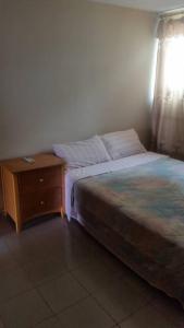 1 dormitorio con cama y mesita de noche de madera en #1 princess self catering apartments, 230mt to senegambia business strip., en Kololi